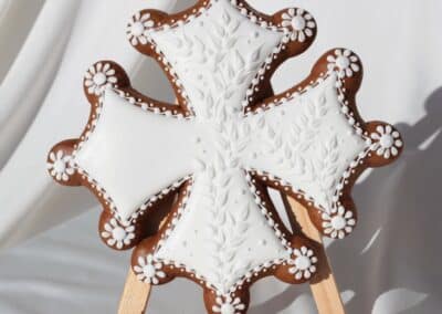 Biscuit décoré en forme de croix d'Occitanie avec glaçage blanc détaillé sur un chevalet.