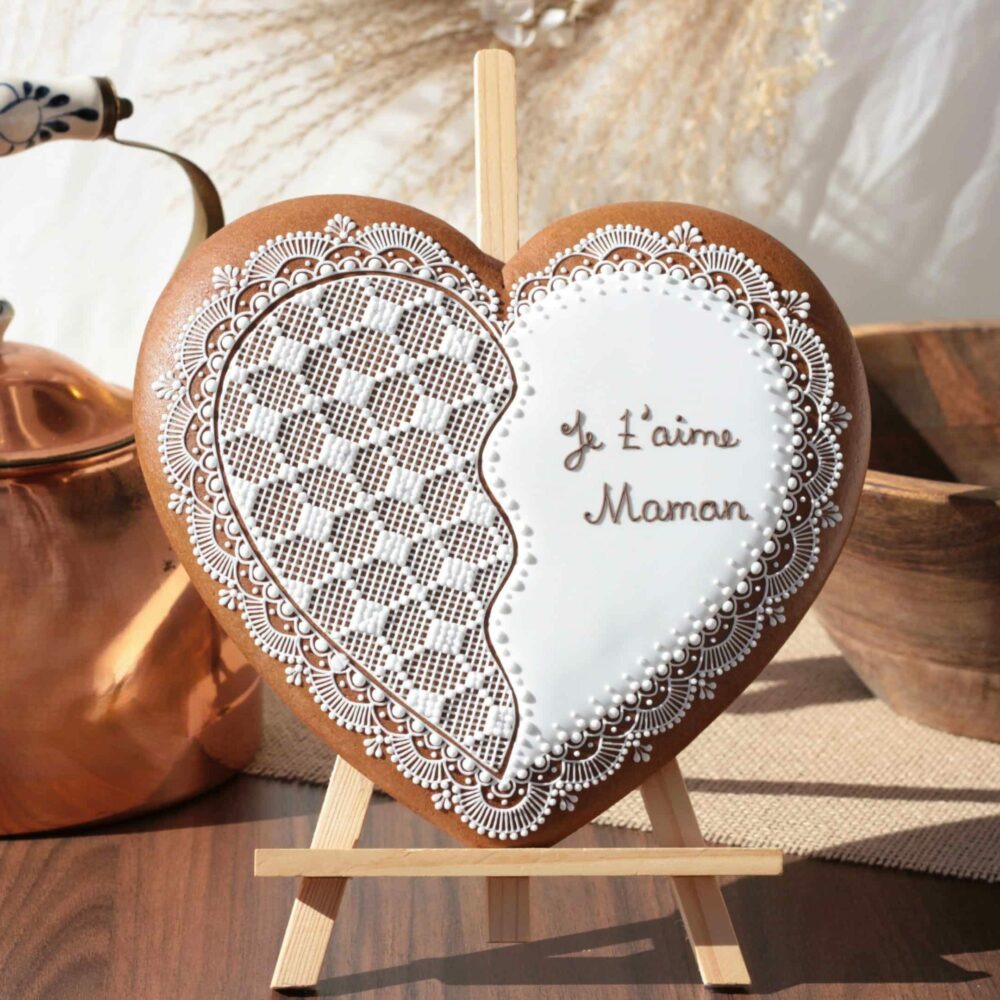 Biscuit en forme de cœur décoré, personnalisé avec l'inscription "Je t'aime Maman", exposé sur un chevalet.